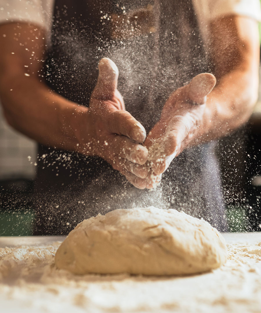 baker putting flour on a loaf of dough